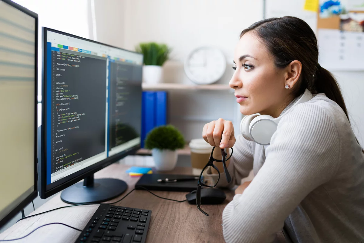 Java-Programmiererin mit schwarzen Haaren, die den Code auf dem Monitor betrachtet