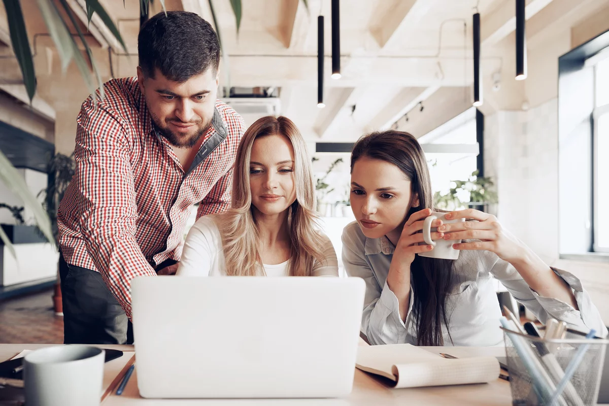 DevOps team of three young people in front of a laptop computer