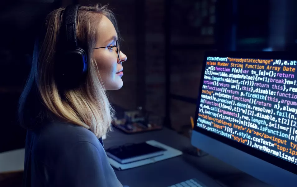 Mláda žena programátorka pozerá do ferbného kódu na monitore